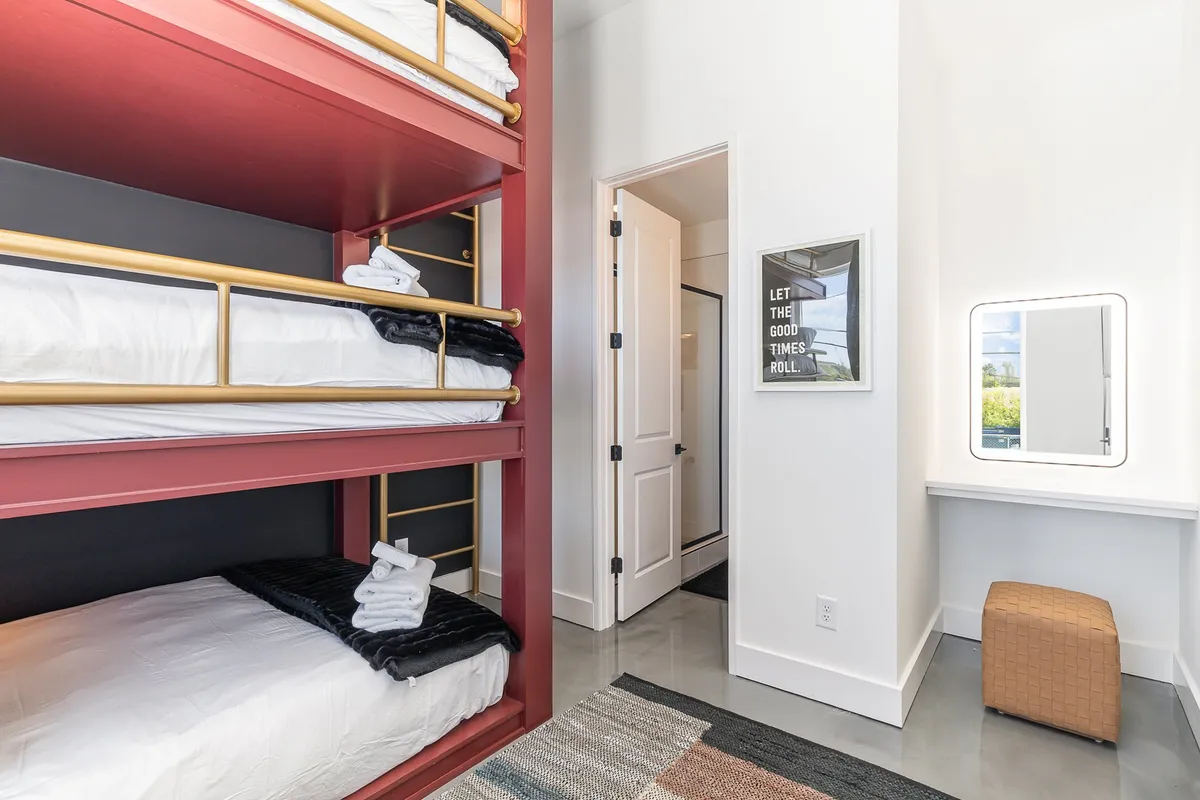 A cheerful kids' room with gold-railed bunk beds, a playful mirror and vanity area, and framed art on the wall. The layout encourages both rest and fun, making it perfect for younger guests to get ready together or share bedtime stories.