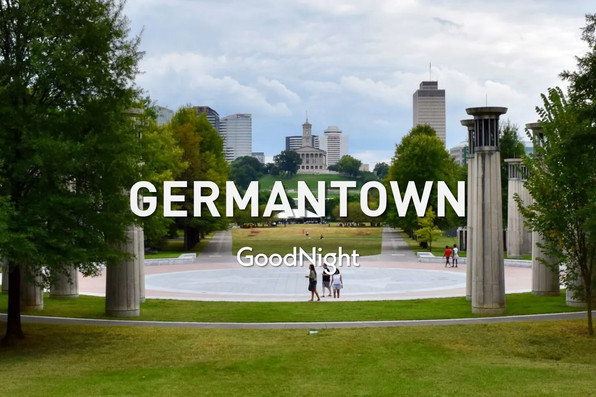 A peaceful central plaza in Germantown with a walking path, lush greenery, and a view of the neighborhood skyline. The scene is relaxed and social, inviting guests to explore the nearby area on foot and enjoy local dining or events.